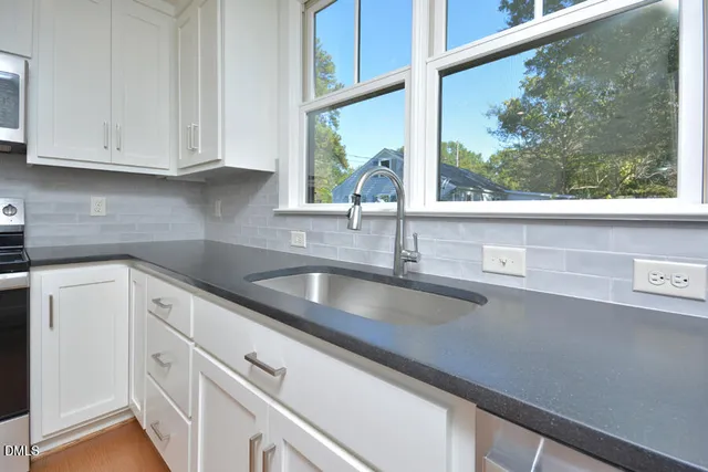 a kitchen with stainless steel appliances white cabinets and a window
