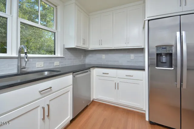 a kitchen with white cabinets and a window
