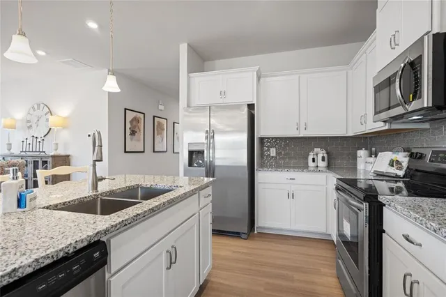 a kitchen with stainless steel appliances granite countertop a sink dishwasher stove and refrigerator