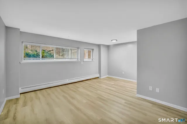 a view of an empty room with wooden floor and a window