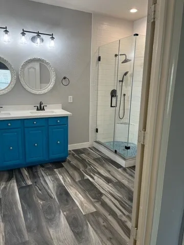 a bathroom with a sink a mirror a vanity and shower