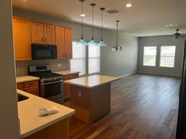 a kitchen with stainless steel appliances granite countertop a stove a refrigerator and a microwave