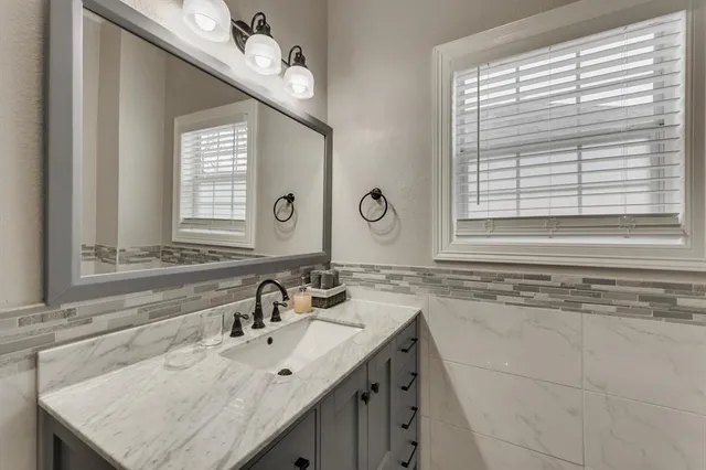 a bathroom with a granite countertop sink and a window