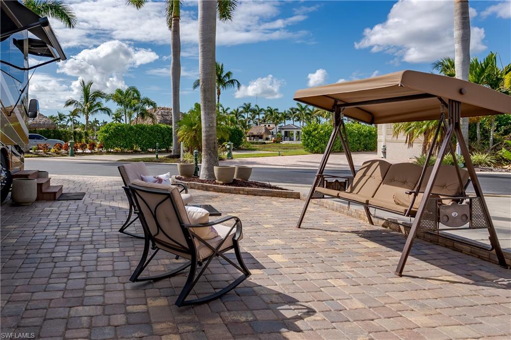 13446 Ladyfish Lane Naples, FL 34114 - Photo 27 of 44 a view of patio with table and chairs under an umbrella with a bench