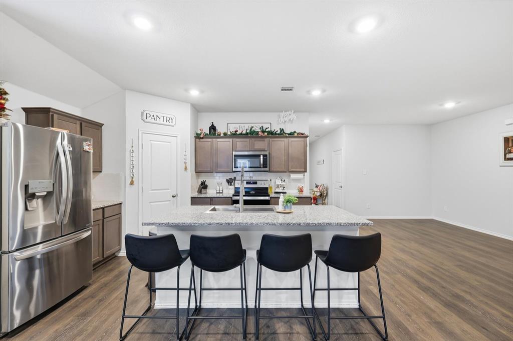2416 Wildhaven Road Crandall, TX 75114 - Photo 7 of 35 a kitchen with stainless steel appliances granite countertop a stove top oven a sink with island and chairs