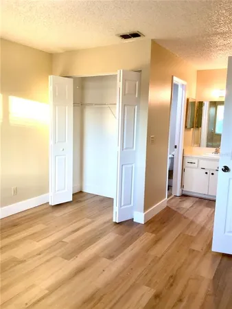 a view of an empty room with wooden floor and a bathroom