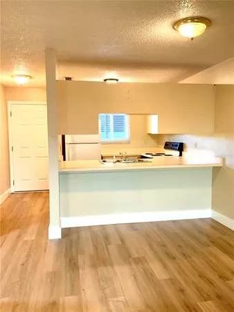 a view of kitchen and empty room with wooden floor