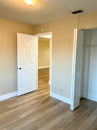 an empty room with wooden floor and a bathroom