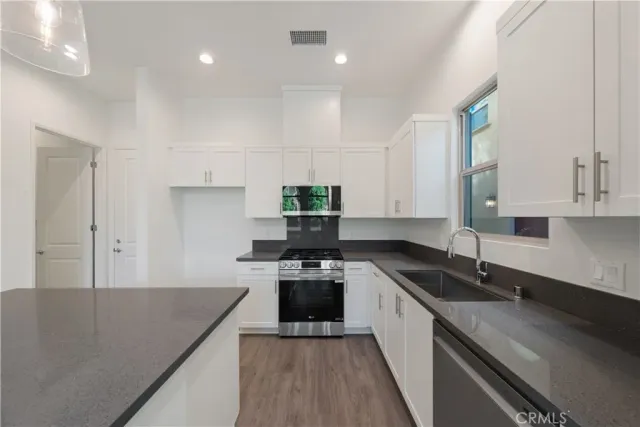 a kitchen with granite countertop white cabinets and white appliances