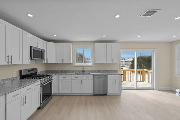 a large kitchen with stainless steel appliances granite countertop a stove a sink a refrigerator and white cabinets