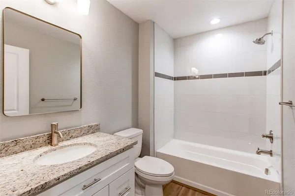 a bathroom with a granite countertop sink toilet mirror and shower
