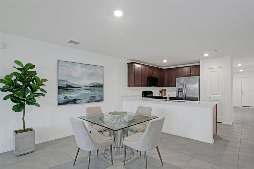 14048 Earlham Street Pilot Point, TX 76258 - Photo 2 of 15 a kitchen with stainless steel appliances kitchen island granite countertop a sink a stove a microwave a dining table and chairs