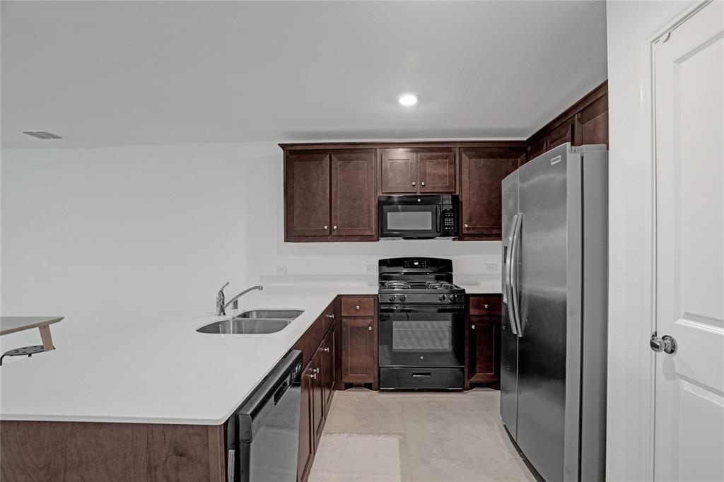 14048 Earlham Street Pilot Point, TX 76258 - Photo 3 of 15 a kitchen with stainless steel appliances a refrigerator and a stove