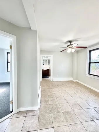 a view of empty room with windows and ceiling fan