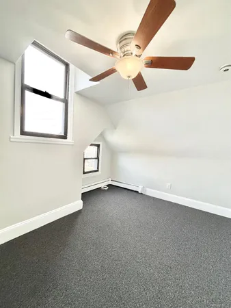 an empty room with a ceiling fan and window