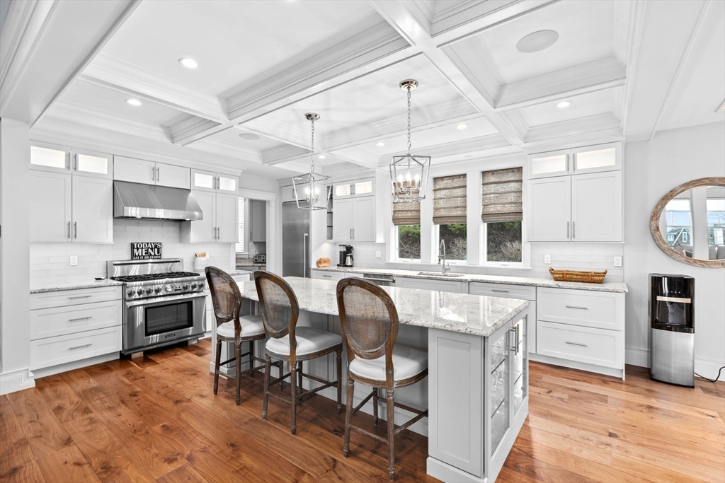 170 Otis Street Hingham, MA 02043 - Photo 11 of 42 a kitchen with stainless steel appliances granite countertop a stove a sink dishwasher a dining table and chairs with wooden floor