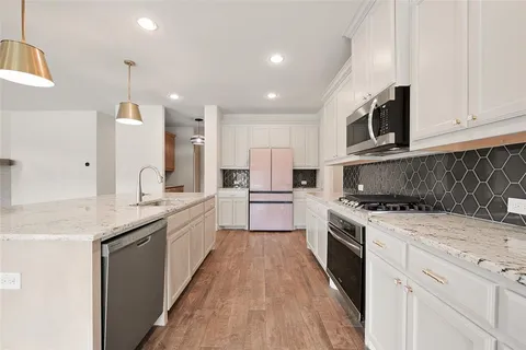 a large kitchen with stainless steel appliances granite countertop a stove a sink and a refrigerator