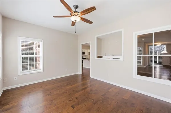 an empty room with wooden floor ceiling fan and window