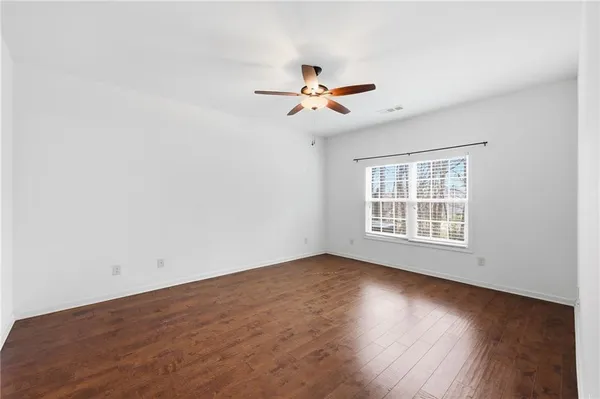 an empty room with wooden floor and ceiling fan