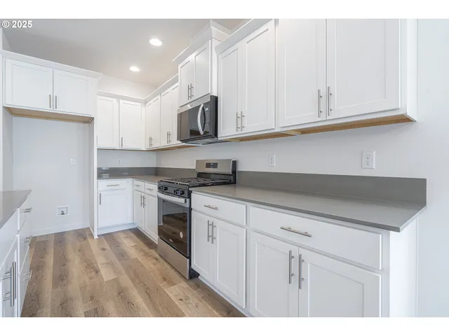 a kitchen with stainless steel appliances granite countertop a sink a stove and white cabinets