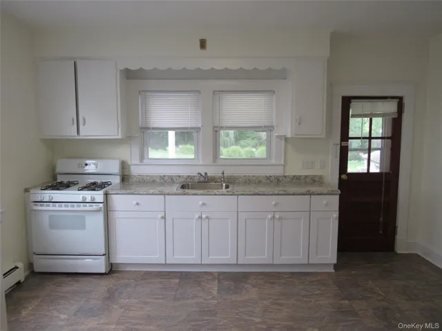 a kitchen with granite countertop white cabinets sink and window
