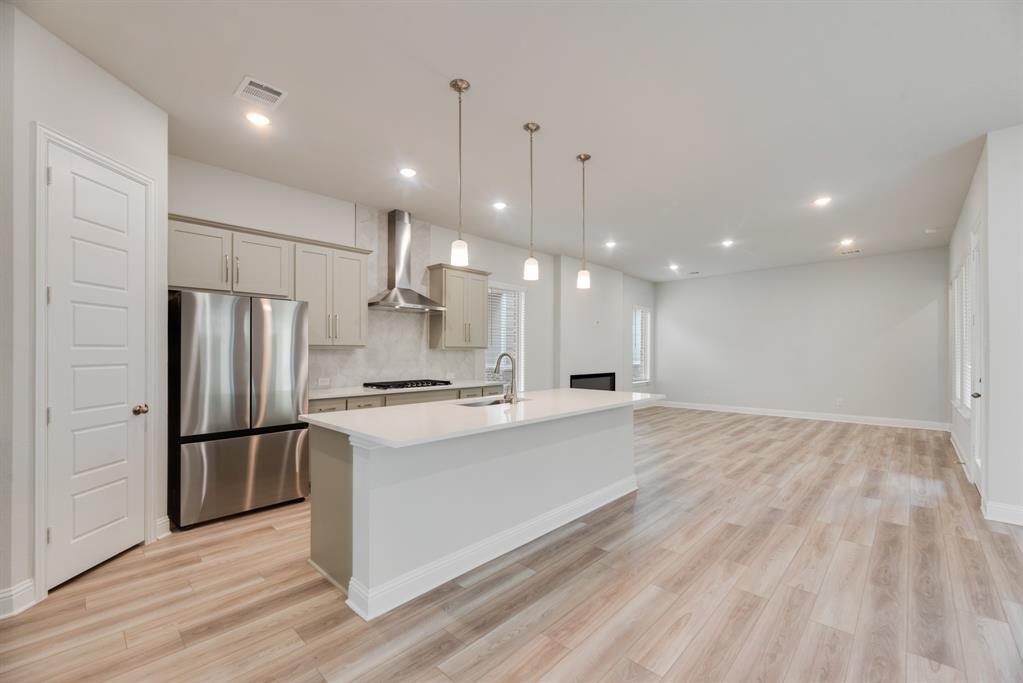 7009 Sunset Boulevard Rowlett, TX 75088 - Photo 7 of 35 a large kitchen with kitchen island a stove a refrigerator a sink and a oven with wooden floor