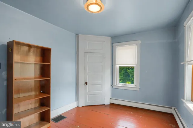a view of an empty room with closet and a window