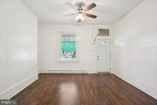 an empty room with wooden floor chandelier fan and windows