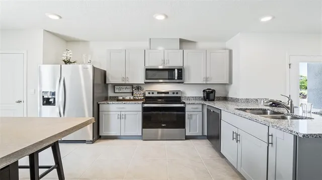 a kitchen with stainless steel appliances a table chairs refrigerator and microwave