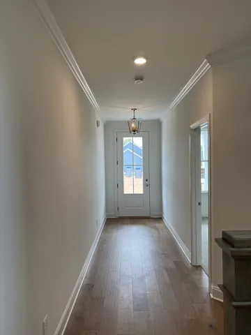 a view of a hallway with wooden floor and chandelier