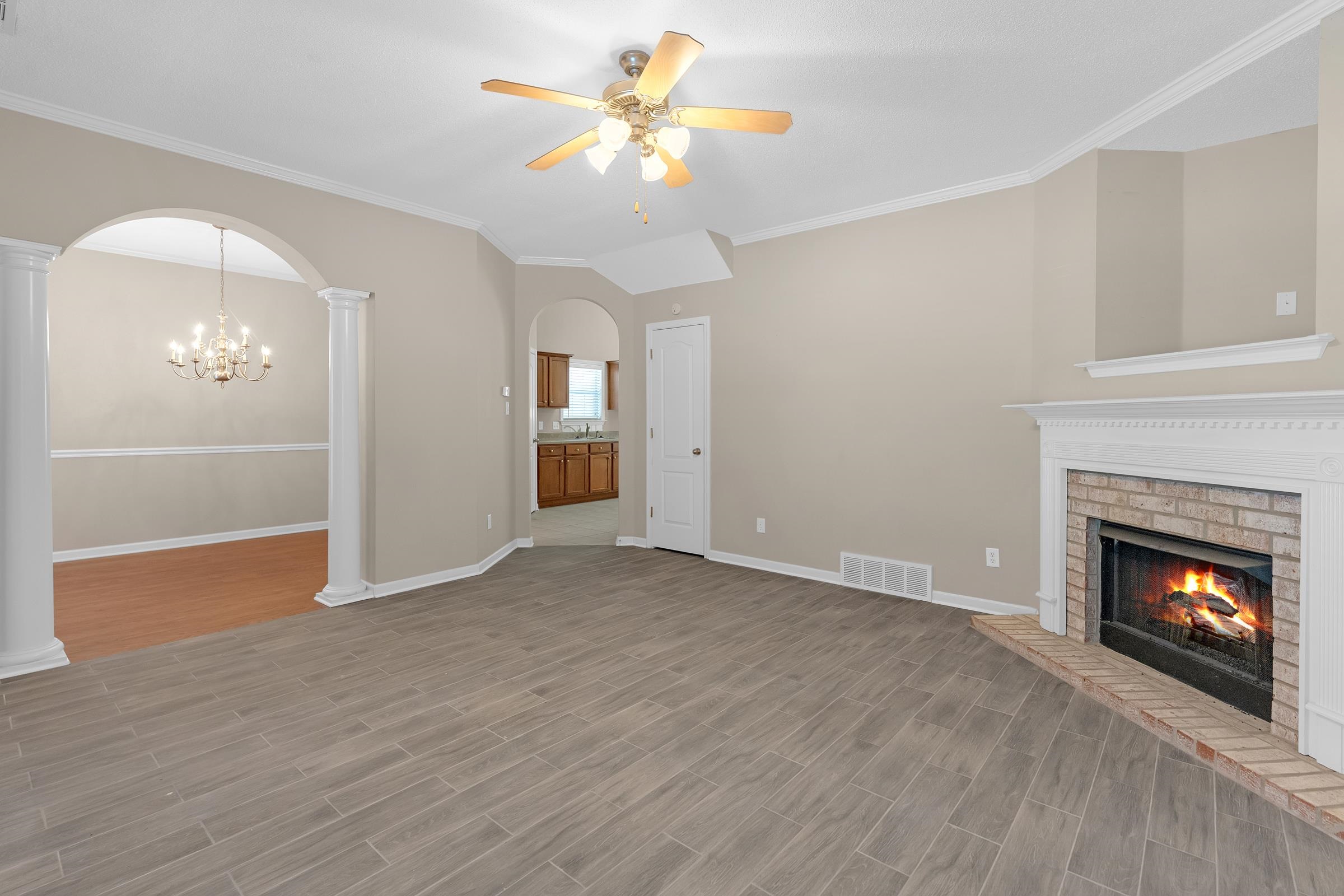 1229 North Sanga Road Memphis, TN 38016 - Photo 3 of 32 Unfurnished living room with wood finish floors, crown molding, arched walkways, a fireplace, and a chandelier