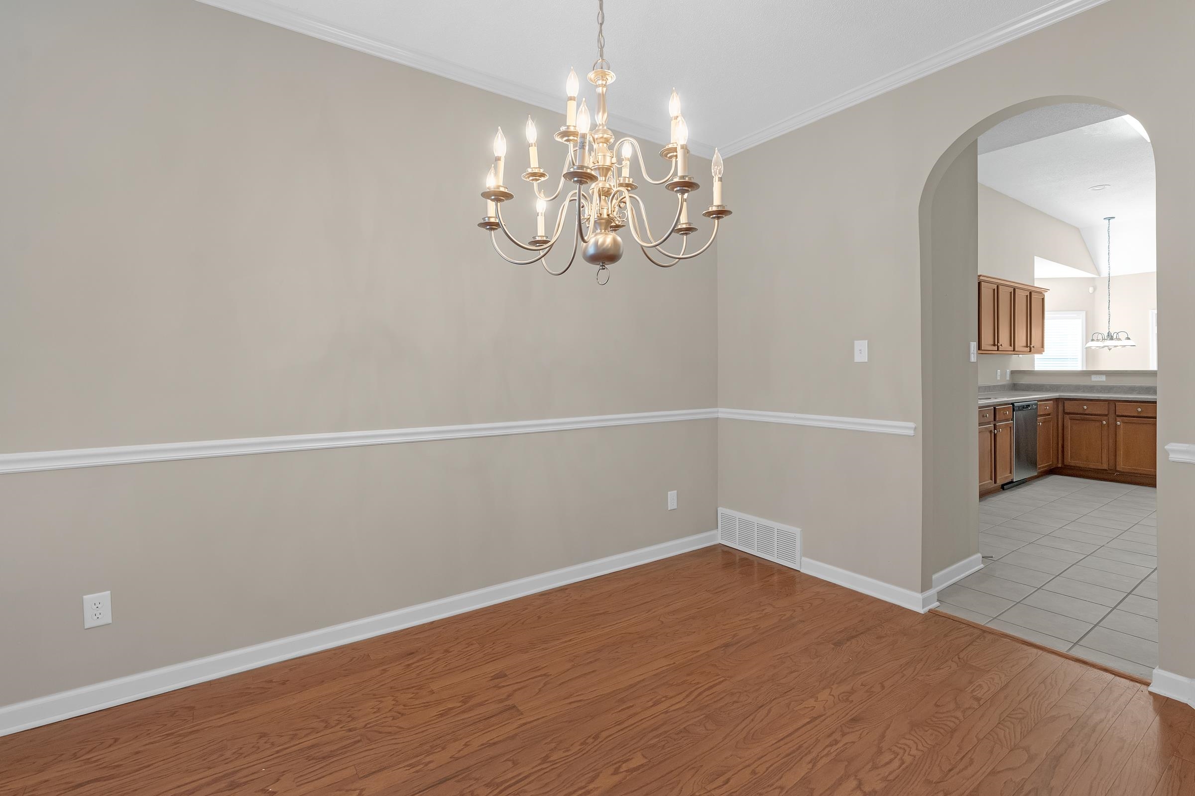 1229 North Sanga Road Memphis, TN 38016 - Photo 5 of 32 Unfurnished dining area featuring light wood-style flooring, arched walkways, ornamental molding, and a chandelier