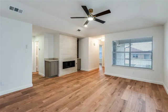 a view of an empty room with window and wooden floor