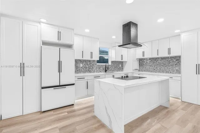 a kitchen with kitchen island white cabinets and stainless steel appliances