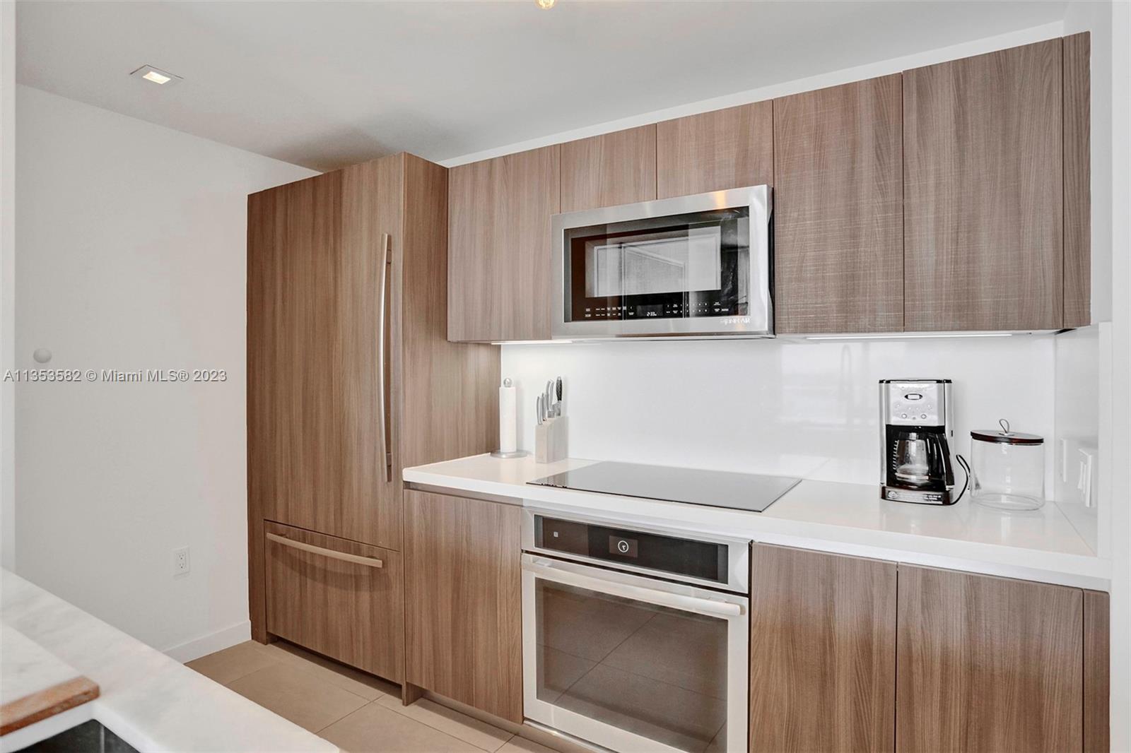 401 North Birch Road, Unit 903 Fort Lauderdale, FL 33304 - Photo 4 of 42 a kitchen with stainless steel appliances wooden cabinets and a stove top oven
