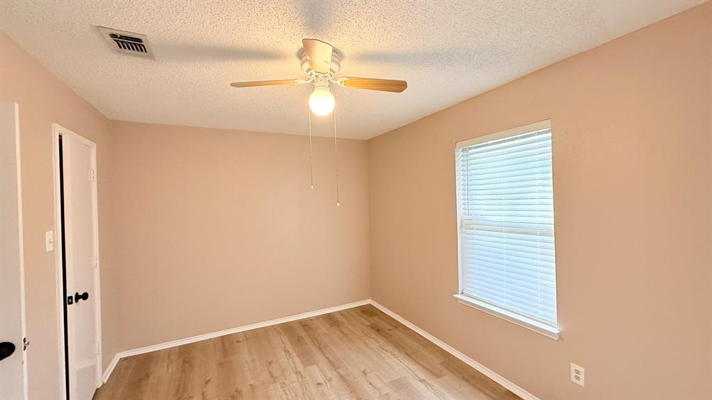 12259 Rim Rock Road Dallas, TX 75253 - Photo 11 of 17 Spare room featuring a textured ceiling, light wood-type flooring, and ceiling fan