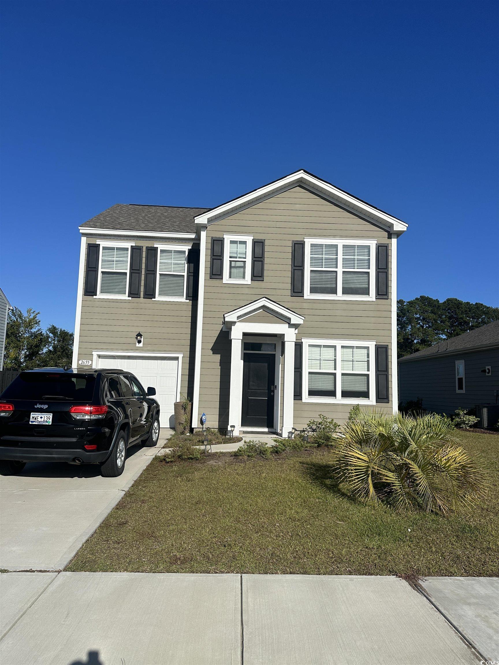 View of front of home featuring driveway, a garage, and a front yard
