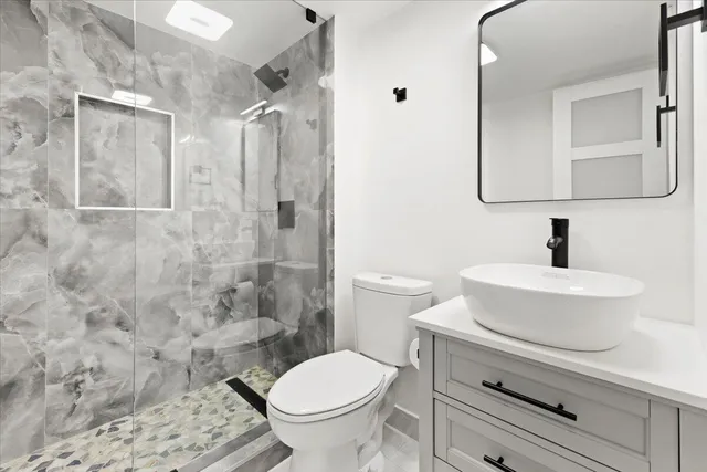 a bathroom with a toilet a sink a shower and mirror