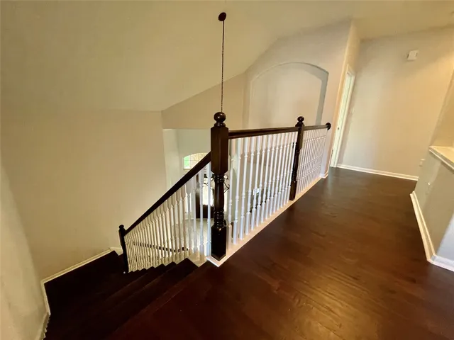 a view of a hallway with wooden floor and stairs