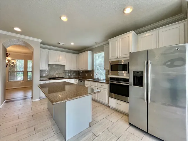 a kitchen with stainless steel appliances granite countertop a refrigerator a sink a stove top oven and a refrigerator