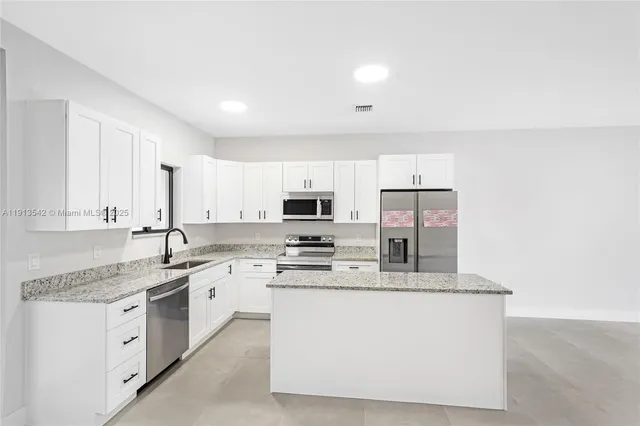 a kitchen with stainless steel appliances granite countertop a refrigerator sink and stove