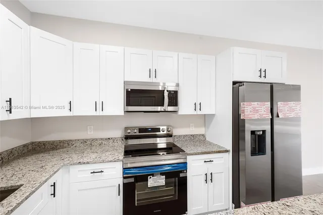 a kitchen with granite countertop a sink stainless steel appliances and cabinets