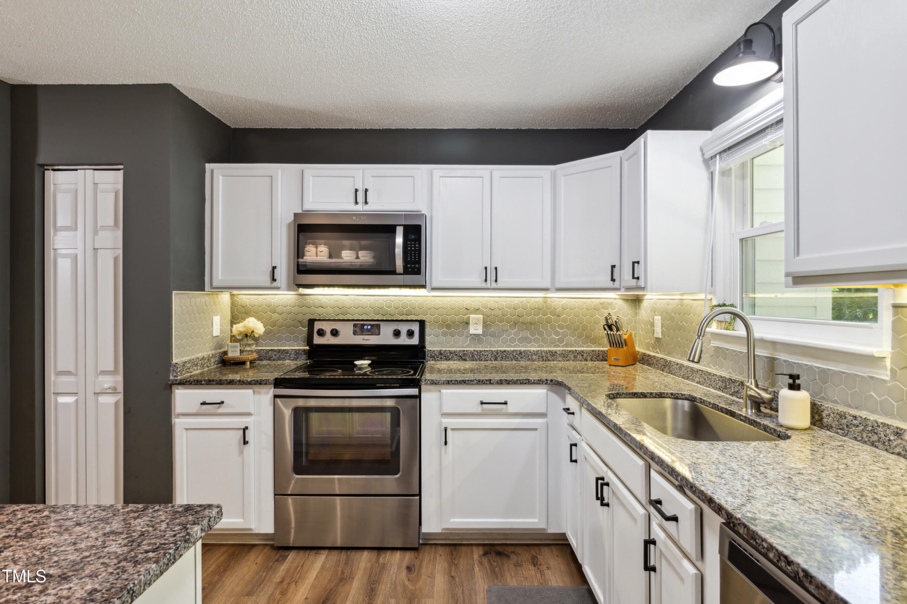 5775 Forest Lawn Court Raleigh, NC 27612 - Photo 15 of 45 a kitchen with granite countertop a sink stainless steel appliances and white cabinets
