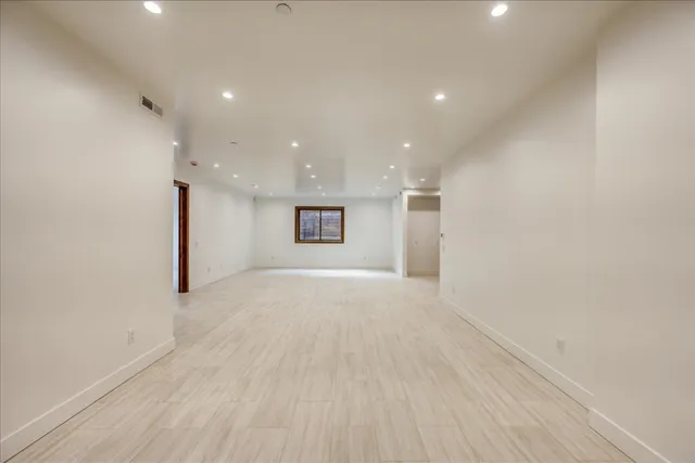 a view of an empty room with a stove and kitchen view