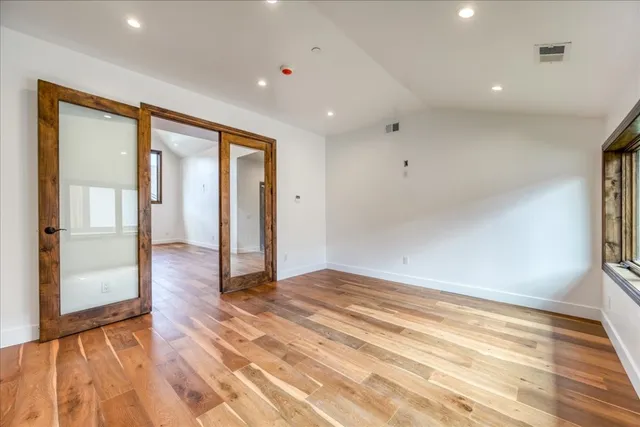 a view of an empty room with a window and wooden floor