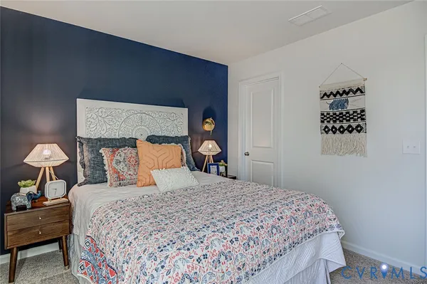 a bedroom with a bed and a lamp on dresser