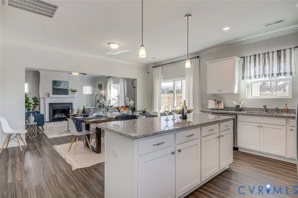 a kitchen with sink stove and white cabinets with wooden floor