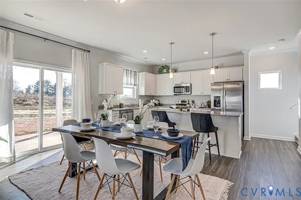 a kitchen with a dining table chairs wooden floor cabinets and appliances