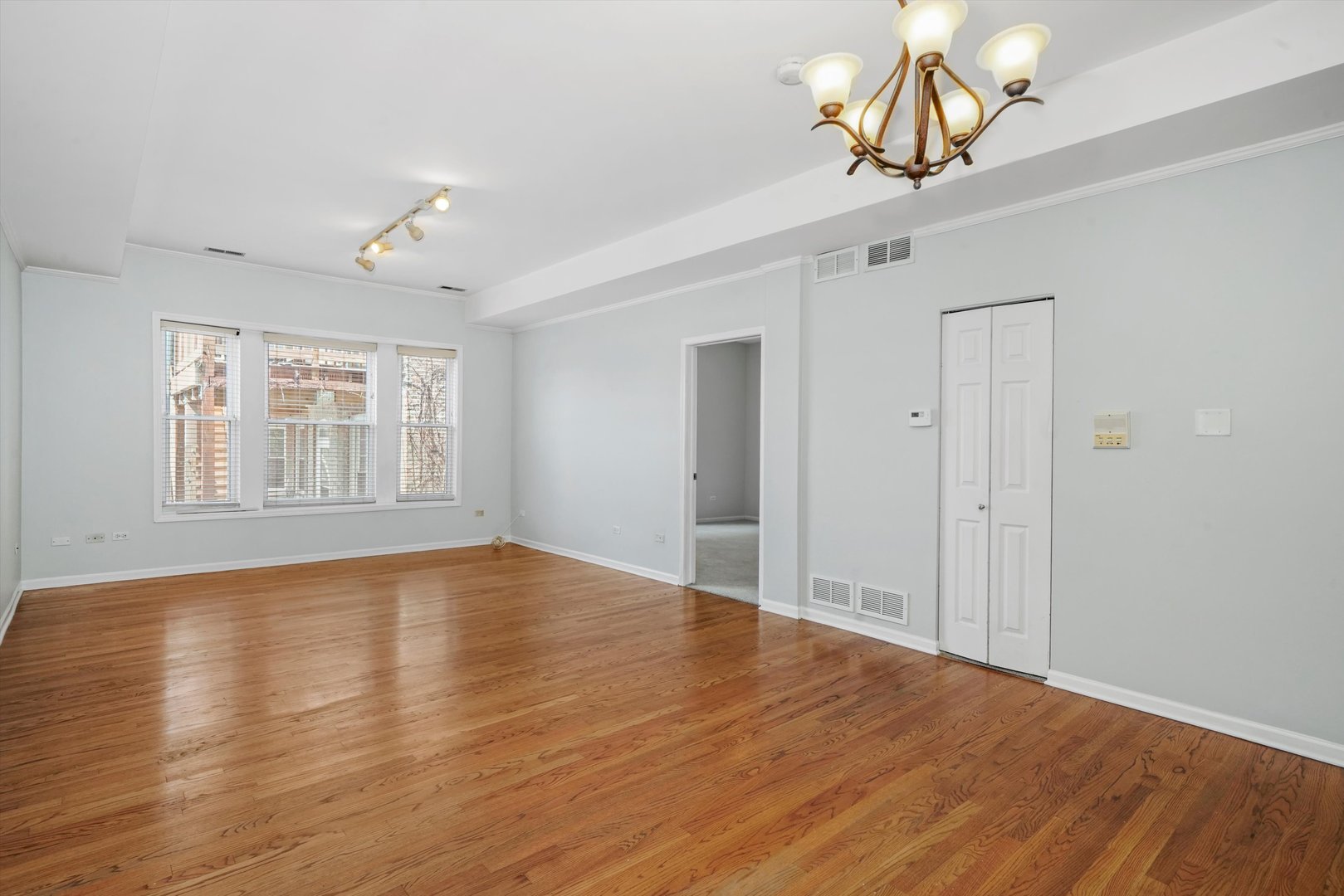 4536 North Sheridan Road, Unit 204 Chicago, IL 60640 - Photo 4 of 24 a view of an empty room with a window and wooden floor