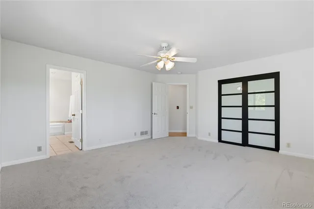 an empty room with windows and ceiling fan